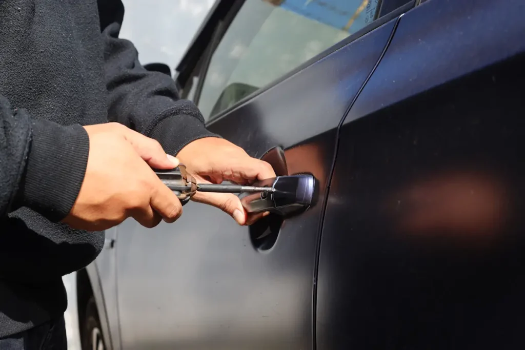 Un homme qui ouvre la porte d'une voiture avec un tournevis